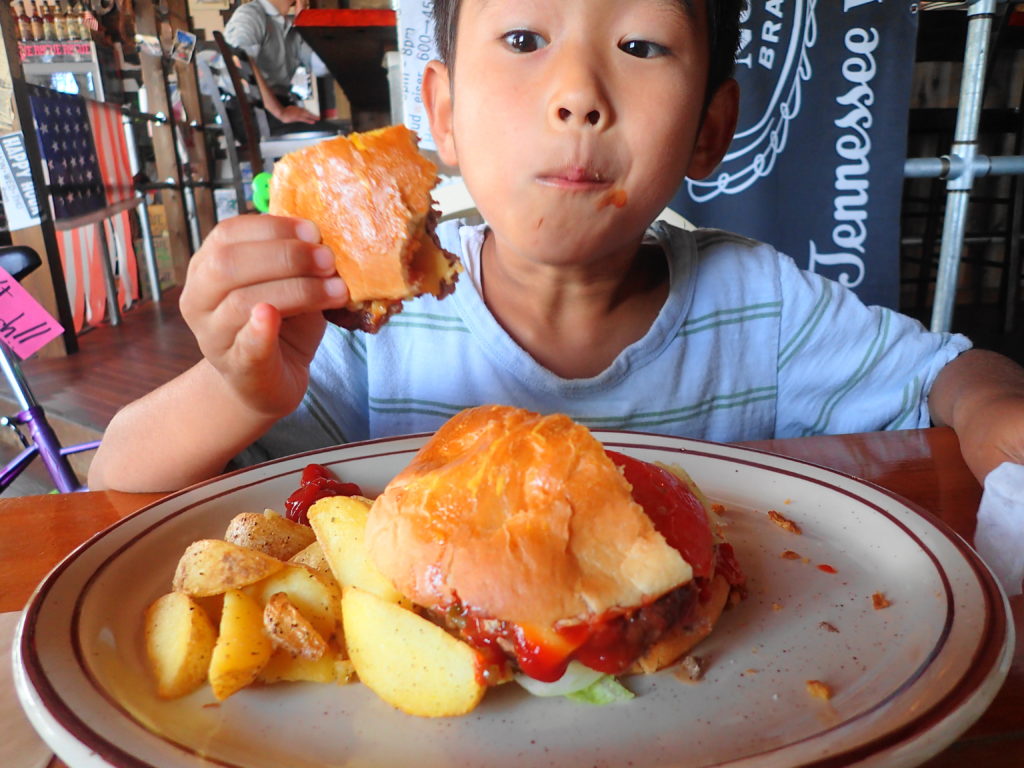 ハンバーガーを夢中で食べる息子